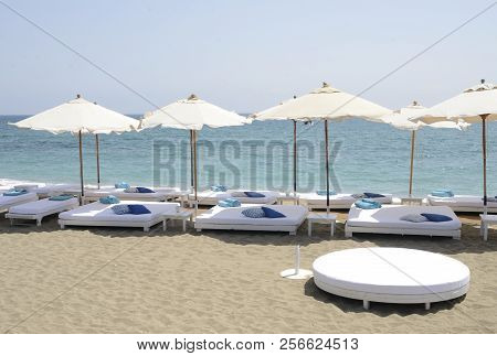 Marbella, Spain - August 31, 2018: Blue Towels And Pilows On White Big Sun Beds At First Line Of Bea