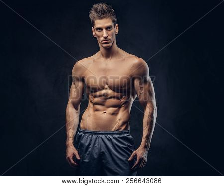 Handsome Shirtless Ectomorph Bodybuilder With Stylish Hair Posing On A Dark Background.