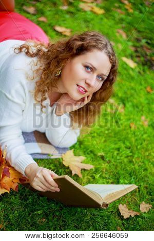 beautiful young plussize woman reading a book   in the autumn park