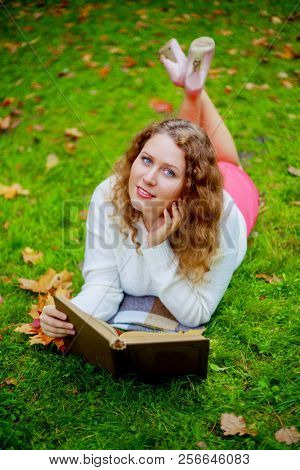 beautiful young plussize woman reading a book   in the autumn park