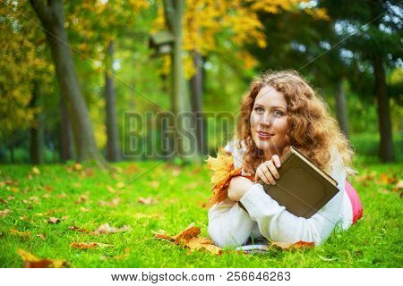 beautiful young plussize woman reading a book   in the autumn park