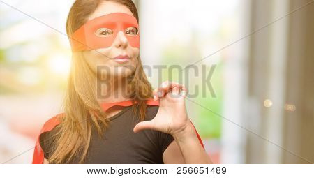 Middle age super hero woman wearing red mask and cape proud, excited and arrogant, pointing with victory face