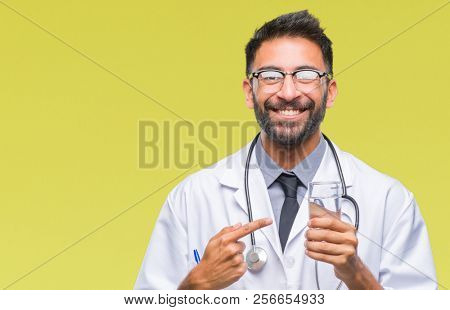 Adult hispanic doctor man drinking glass of water over isolated background very happy pointing with hand and finger