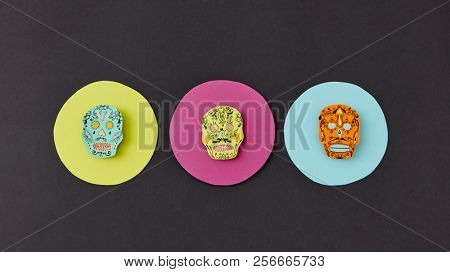 Decorative pattern from round frames with creative handmade skulls on a black paper background. Flat lay. Calaveras simbol of the Mexican holiday of Calaca. Flat lay