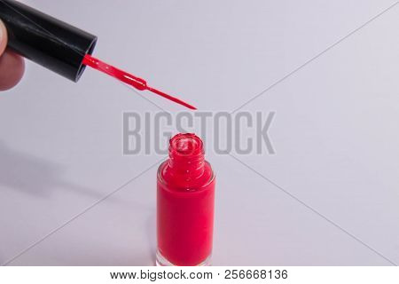 An Open Can Of Red Lacquer And A Brush With A Drop Of Lacquer On It