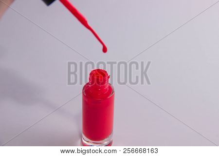 An Open Can Of Red Lacquer And A Brush With A Drop Of Lacquer On It