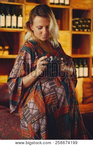 Portrait Of A Young Pregnant Pensive Blond Woman Holding And Looking On Photo Camera, Wine Chiller C