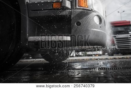 Pressure Washing Semi Truck Closeup Photo. Wet Tractor Bumper. Clean Vehicle Concept Photo.