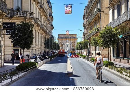Montpellier, France - June 24, 2015: Triumphal Arch Porte Du Peyrou. Rue Foch Street. Woman Is Ridin