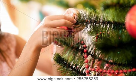 Closeup Image Of Girls Hands Putting Red Bauble On Christmas Tree