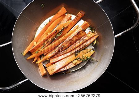 Root Vegetables, Glazed Carrots With Thyme, Ginger And Honey In An Iron Pan On The Black Stove, High