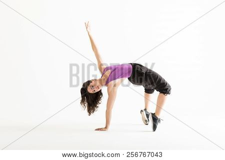 Confident Female Dancer With Arm Raised Bending Backwards Over Plain Background