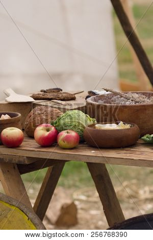 Medieval Food Preparation Including Bread, Butter, Cheese, Fruit In Wooden Bowls Or Trenchers