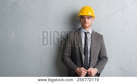 Young redhead man wearing architect outfit and helment with a confident expression on smart face thinking serious