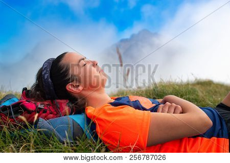 Girl Sleeping With Her Head On The Backpack In A Mountain Meadow During An Excursion.