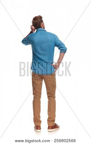 back view of a young casual man scratching his head on white background