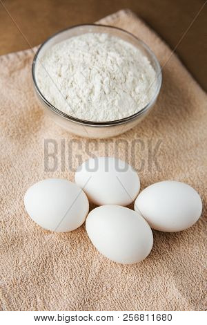 White Chicken Eggs And Bowl With Flour On Brown Towel