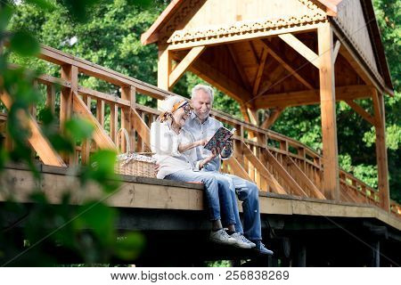 Retired Married Couple Looking At Their Family Photo Album