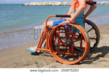 Young Boy On The Wheelchair In Summertime On The Beach