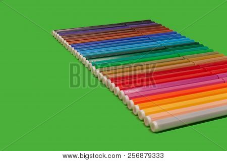 Row Of Various Bright Plastic Multicolored Felt Pens Lying On A Green Surface. Concept Of Creativity