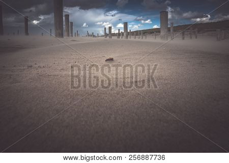 Long Shutter Photo Of Wooden On Sandy Beach With White Clouds And Waves Of The North Sea