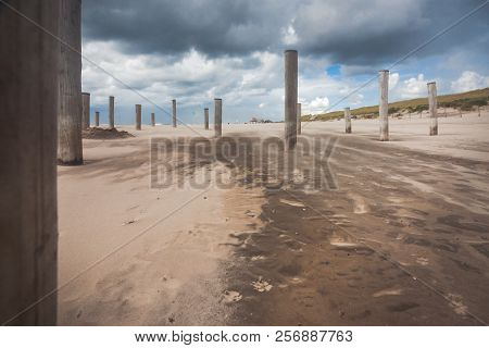 Long Shutter Photo Of Wooden On Sandy Beach With White Clouds And Waves Of The North Sea