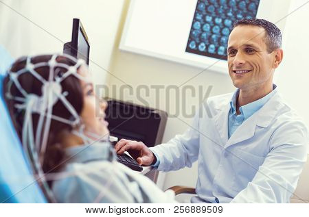 Friendly Looking Doctor Smiling While Conducting Electroencephalography Analysis