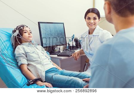 Scared Little Girl Undergoing Electroencephalography Procedure At Lab