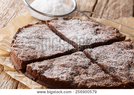 Swedish Chocolate Sticky Cake With Powdered Sugar Close-up On The Table. Horizontal