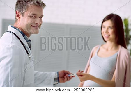 Delighted Positing Doctor Giving A Thermometer To His Patient