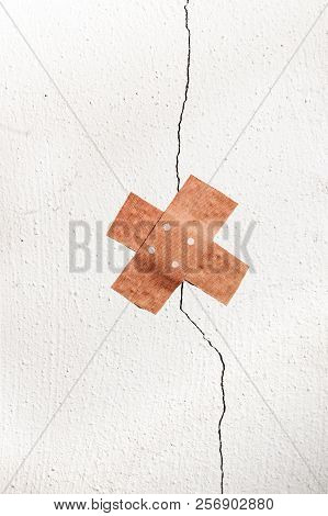 Wound Plaster In Cross Shape On A Crack In The Wall, Concept For Botched Renovation And Doctoring Ar