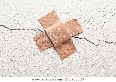 Wound Plaster In Cross Shape On A Crack In The Wall, Concept For Botched Construction And Doctoring 