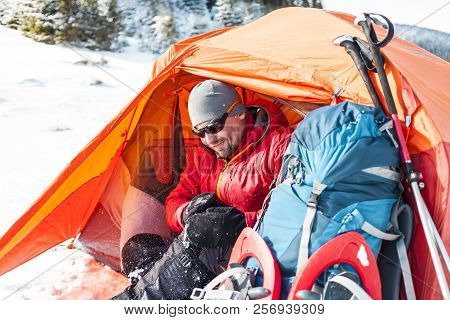 Camping In The Snow. Winter Trekking In The Mountains. Orange Tent, Snowshoes And Trekking Poles. A 