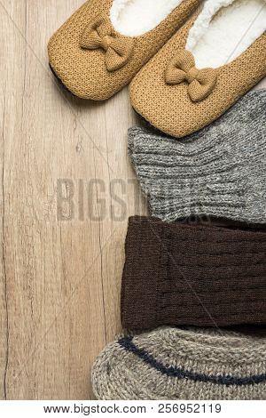Handmade Warm Knitted Socks From Rough Wool Yarn Fluffy Fir Slippers On Wood Background. Winter Autu