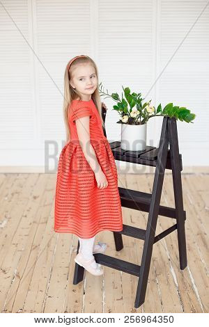Young Little Blonde Girl Standing On Scaling-ladder Cares For Flowers