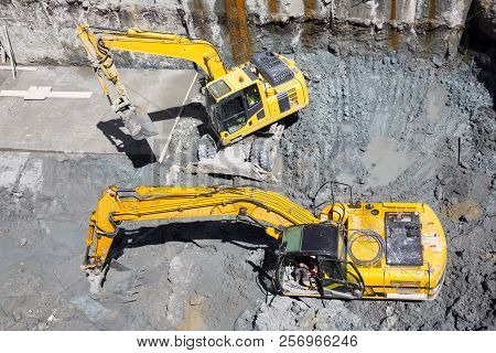 Excavators Dig At A Construction Site Of A Street And A Subway. Baggers Transport Dirt To A Higher L