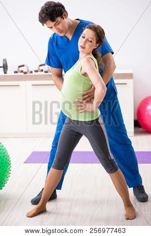 Pregnant woman doing physical exercies with instructor