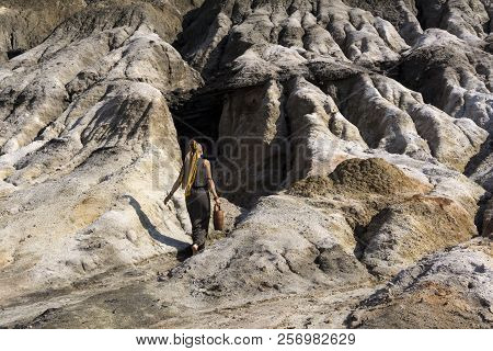 Girl In A Headscarf And A Long Dress With A Clay Jug Goes To The Aisle In The Mountain