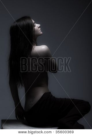 สตูดิโอภาพเหมือนของหญิงสาว topless เจียมเนื้อเจียมตัวใน semidarkness