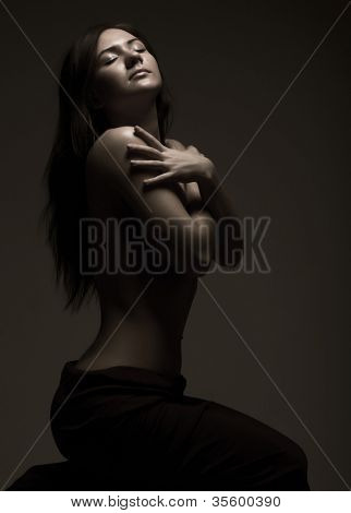 สตูดิโอภาพเหมือนของหญิงสาว topless เจียมเนื้อเจียมตัวใน semidarkness