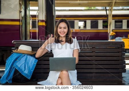 Medium Close Up Beautiful Young Asian Woman In A White Dress With Jeans Jacket Over Backpack At Side
