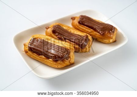 Copy Space. Plate Custard Cakes With Chocolate Icing On A White Background.
