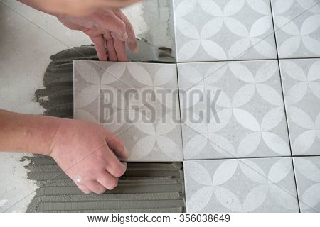 Tiler laying the ceramic tile on the floor. Professional worker makes renovation. Construction. Hands of the tiler. Home renovation and building new house