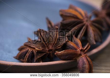 Star Anise With And Without Seeds, In A Clay Dish On A Light Wooden Surface. Spice For The Recipe. B
