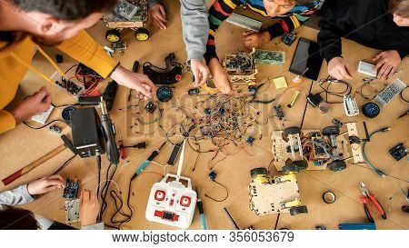 Top View Of A Table With Engineering Tools And Details Lying On It. Children Working With Wires, Con