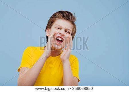 Enervant Preteen Boy Looks At Camera And Screaming In Yellow T-shirt Isolated On Yellow Background, 