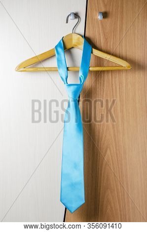 A Mans Blue Tie Hangs On The Door Of The Chiffonier. The Concept Of A Successful Mans Style.