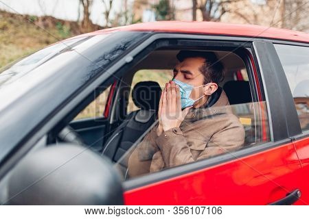 Ill Man Sitting In Car Wearing Protective Mask Coughing Having Flu Coronavirus. Prohibition Driving 