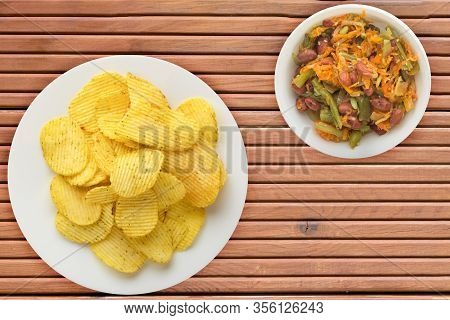 Potato Chips On A White Plate With Vegetarion Salad. Chips On A Orange Wooden Background Top View.