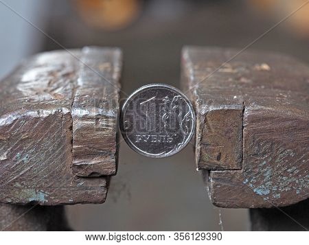 Coin One Russian Ruble Clamped By A Metal Vice On Both Sides. Concept Of Financial And Business Prob